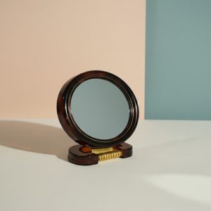 Modern double-sided vanity mirror with a brown patterned frame on a clean peach and teal background.